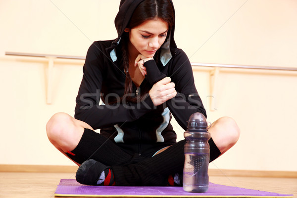 Young pensive fit woman sitting on the yoga mat at gym Stock photo © deandrobot