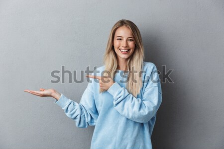 Smiling businesswoman in gesture of asking over gray background Stock photo © deandrobot