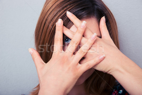 Woman looking at camera through fingers Stock photo © deandrobot
