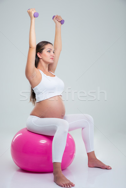 Pregnant woman lifting dumbbells on a fitness ball Stock photo © deandrobot