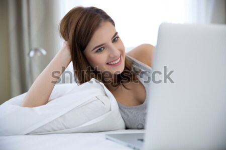 Lány ágy laptop portré mosolyog fiatal lány Stock fotó © deandrobot