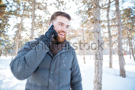 Smiling man talking on the phone in winter park Stock photo © deandrobot