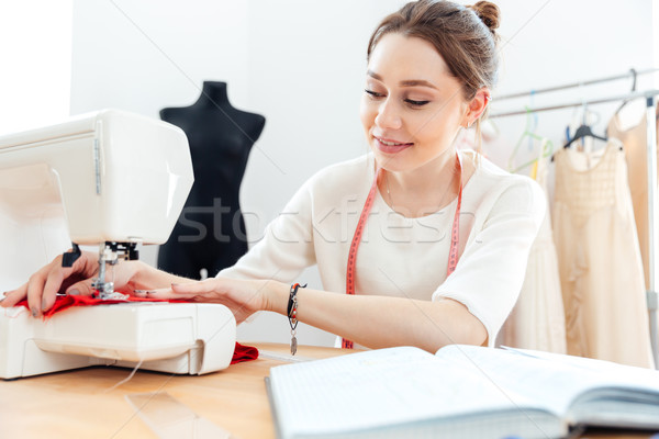 Smiling woman seamstress sews on the sewing machine Stock photo © deandrobot