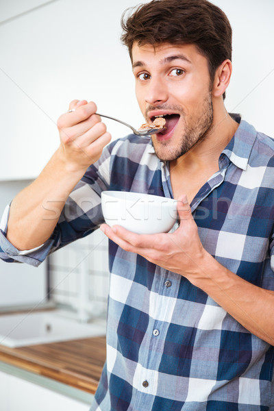 Stock photo: Man having breakfast and eating cereals with milk on kitchen