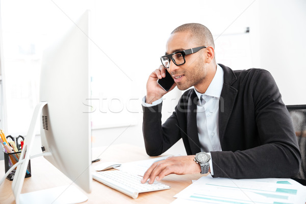 Office worker calling on the phone and reading business document Stock photo © deandrobot