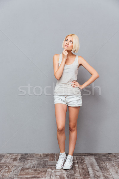Pensive pretty young woman standing and thinking Stock photo © deandrobot