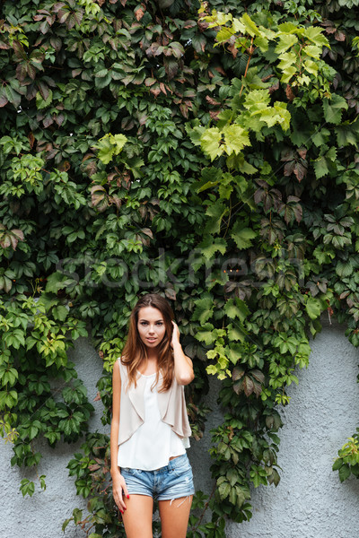 Young cheerful girl posing outdoors with green leaves background Stock photo © deandrobot