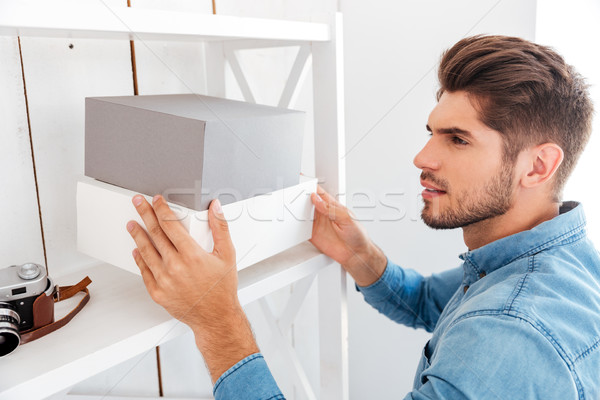 Hanadsome young man putting boxes on the shelf Stock photo © deandrobot