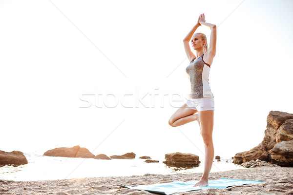 Young woman standing in yoga pose on one leg Stock photo © deandrobot