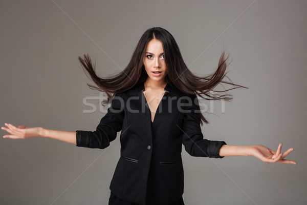 Tineri bruneta femeie costum negru în picioare care zboară Imagine de stoc © deandrobot