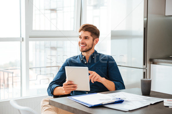 Young man in office analyzing finances with tablet Stock photo © deandrobot