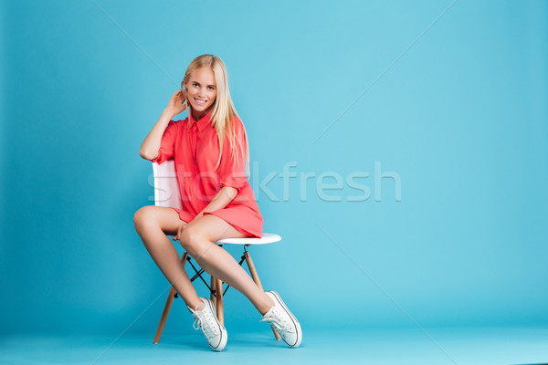 Casual woman in red dress sitting and looking at camera Stock photo © deandrobot