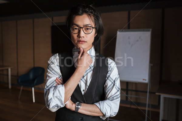 Attractive young asian man looking at camera. Coworking concept. Stock photo © deandrobot