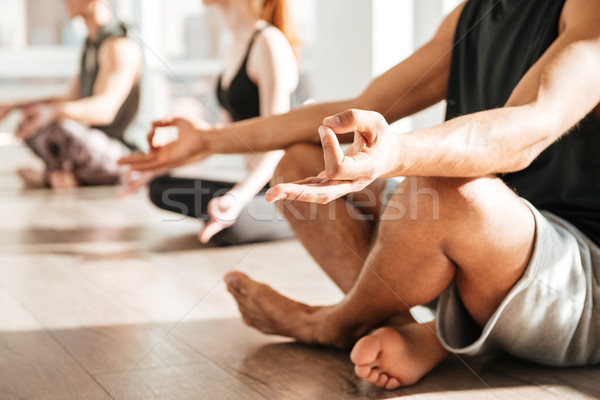 Man sitting and meditating in lotus pose with group Stock photo © deandrobot