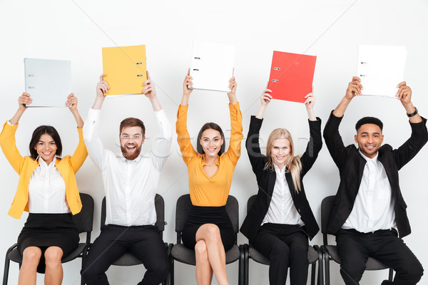 Cheerful colleagues sitting in office holding folders. Stock photo © deandrobot