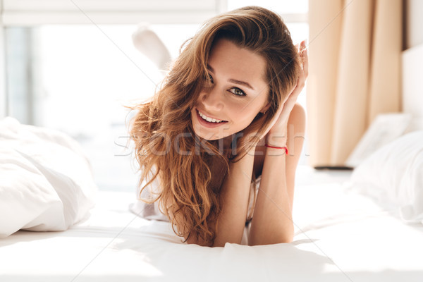 Portrait of brunette woman lying in bed and looking camera Stock photo © deandrobot