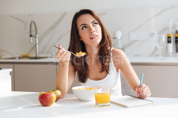 Jeunes femme céréales de petit déjeuner écrit notepad Photo stock © deandrobot