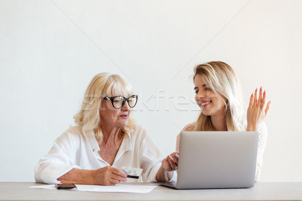 Stock photo: Smiling young lady sitting at home with her grandmother