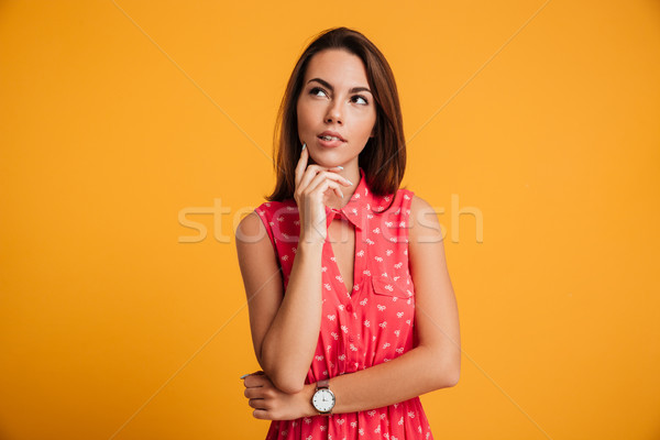 Photo of thinking young woman in red dress touching her chin, lo Stock photo © deandrobot