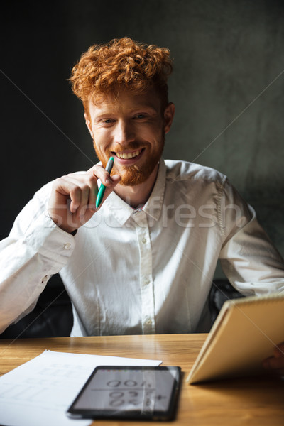 Close-up portrait of young happy readhead curly man, sitting at  Stock photo © deandrobot