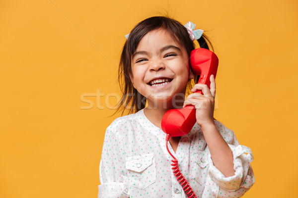 Happy excited little girl talking by red retro telephone. Stock photo © deandrobot