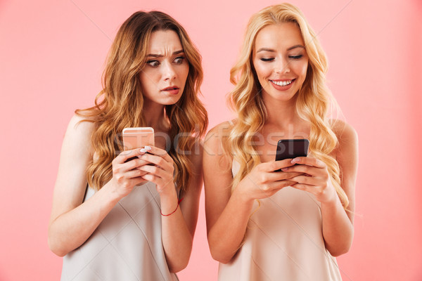 Two young pretty women in pajamas using smartphones Stock photo © deandrobot