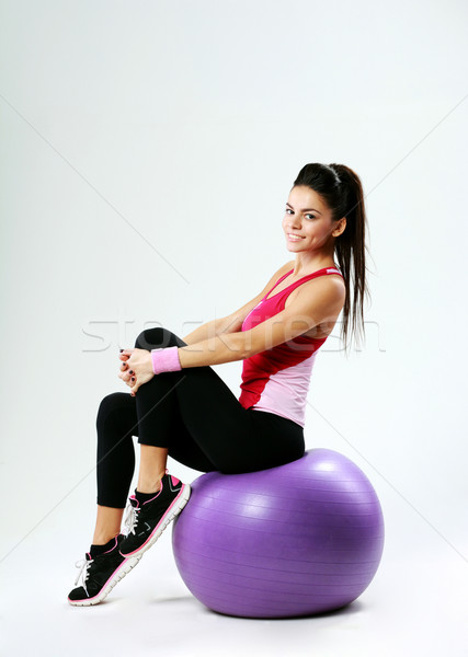 Young happy sport woman sitting on fitball on gray background Stock photo © deandrobot