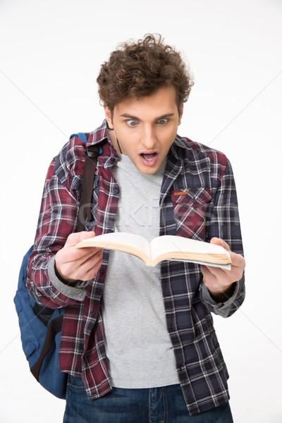 Surprised young man looking on notebook ober gray background Stock photo © deandrobot