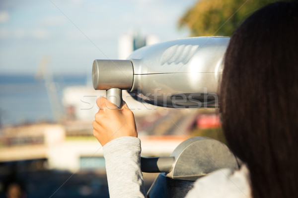 Stock photo: Girl looking in binoculars at the city