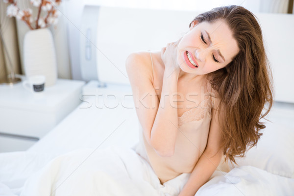Dość młoda kobieta szyi ból posiedzenia bed Zdjęcia stock © deandrobot