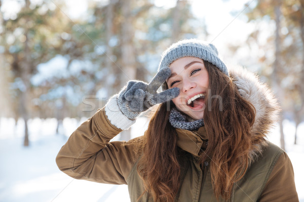 Woman showing peace sign in winter park Stock photo © deandrobot