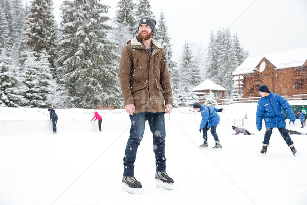 Happy man in ice skates looking away outdoors Stock photo © deandrobot