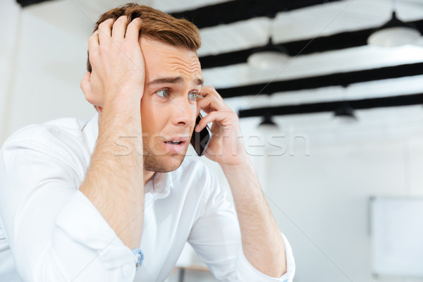 Fiatal üzletember beszél mobiltelefon iroda férfi Stock fotó © deandrobot