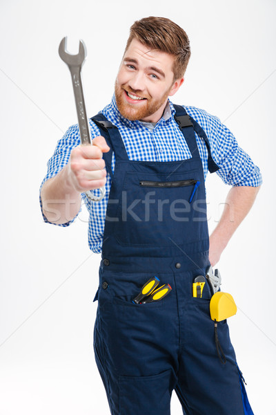 Smiling bearded young man standing and showing wrench Stock photo © deandrobot