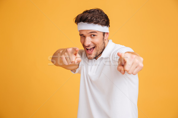 Playful young man athlete winking and pointing on you Stock photo © deandrobot