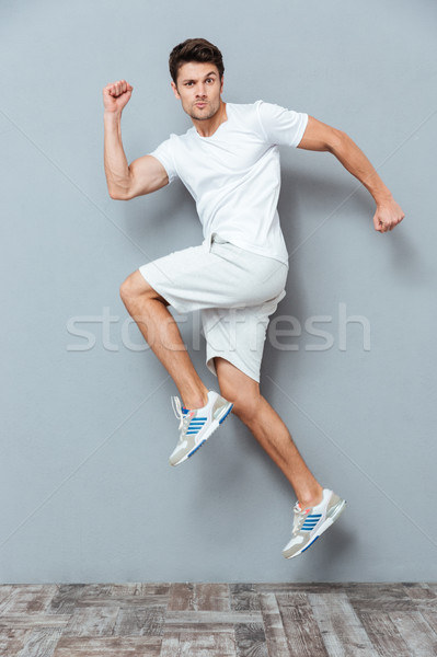 Funny man jumping over gray background Stock photo © deandrobot
