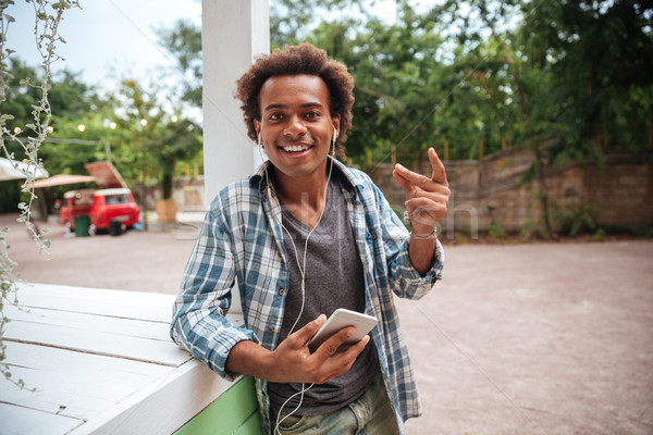 Happy african young man listening to music from cell phone Stock photo © deandrobot