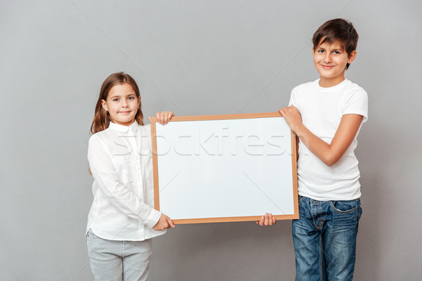 Smiling little boy and girl holding blank white board Stock photo © deandrobot