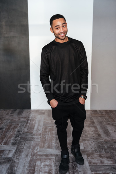 Full length of cheerful african young man in black clothes Stock photo © deandrobot