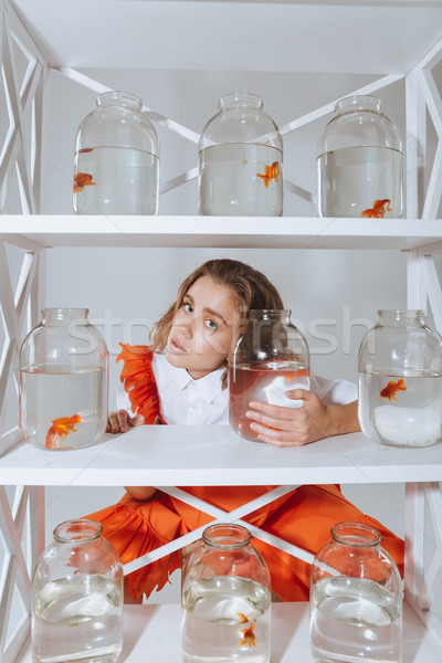 Woman looking through the closet with gold fishes in jars Stock photo © deandrobot