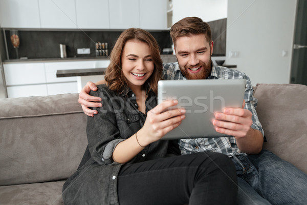 Stock photo: Happy loving couple in kitchen using tablet computer.