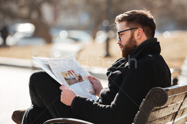 Man in glasses sitting and reading newspaper at the city Stock photo © deandrobot