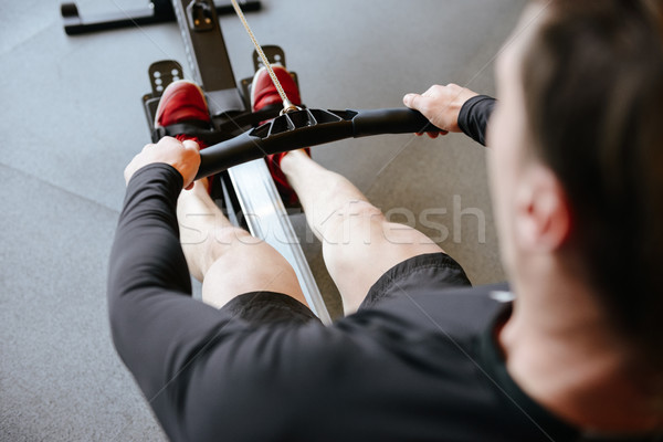 Back view of Athletic man using rowing machine Stock photo © deandrobot