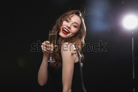 Cheerful beautiful young woman drinking champagne and winking Stock photo © deandrobot