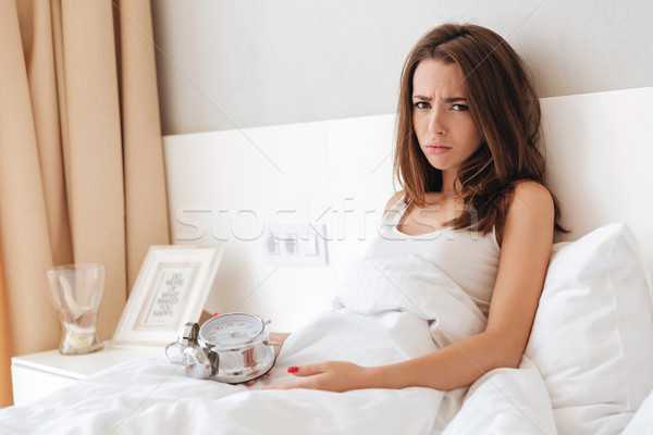 Disappointed young girl holding alarm clock Stock photo © deandrobot
