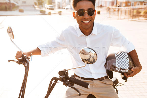 Smiling african man sitting on modern motorbike outdoors Stock photo © deandrobot