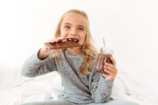 Close-up photo of funny little girl eating chocolate bar looking Stock photo © deandrobot