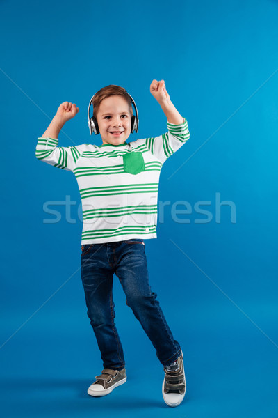 Full length image of carefree young boy listening music Stock photo © deandrobot