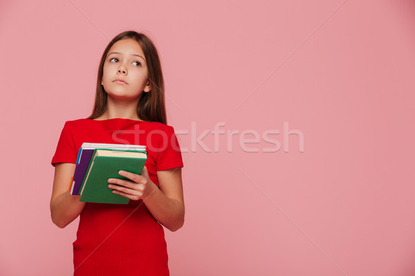 Pensive girl pupil looking at copy space and holding books Stock photo © deandrobot