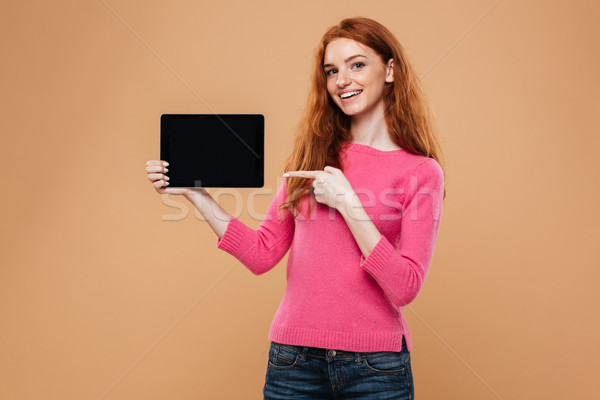 Stock photo: Portrait of a smiling pretty redhead girl pointing finger